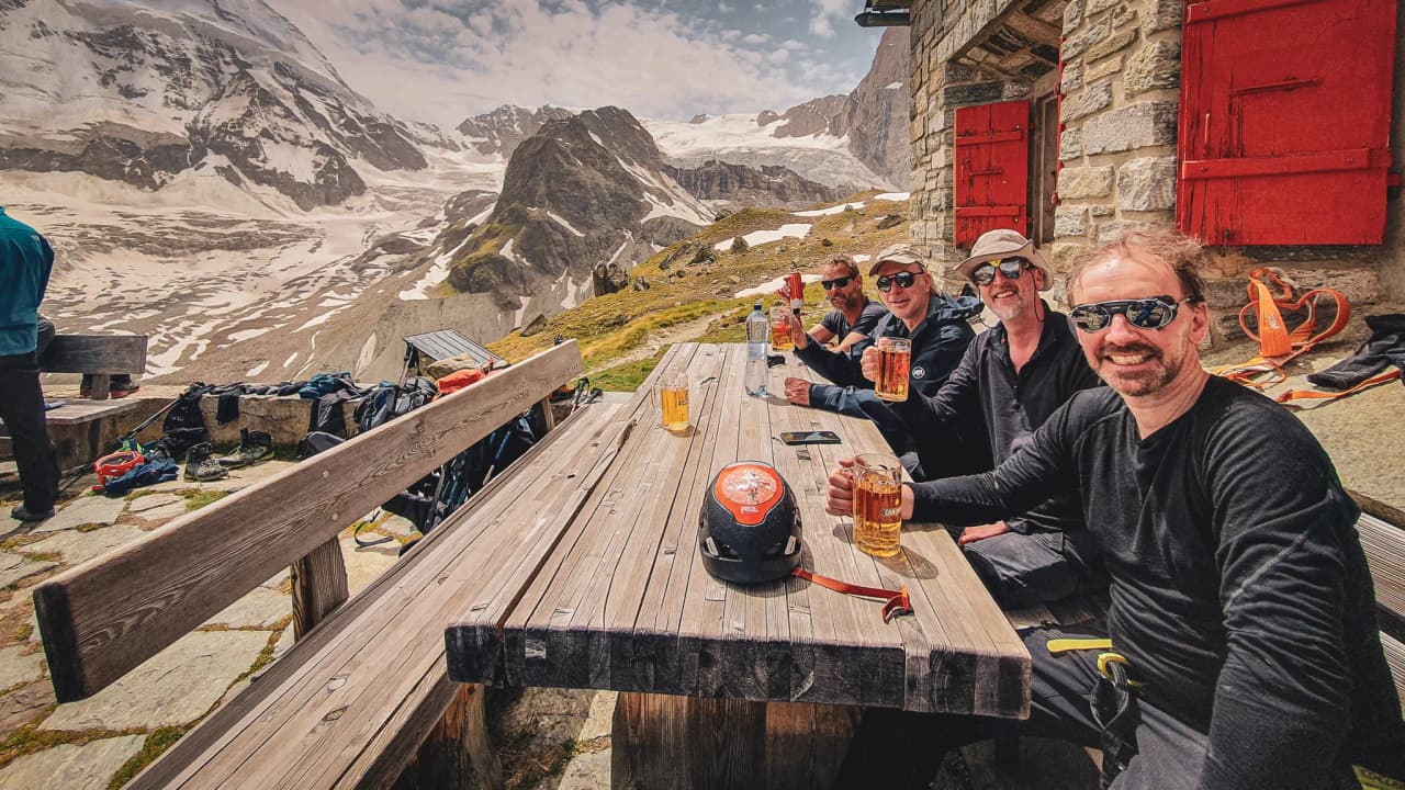 A group of adventurers enjoying beers in the mountains, with a breathtaking glacial panorama.
