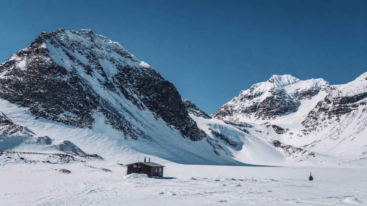 Een schilderachtig berghut aan de voet van majestueuze besneeuwde bergen, het ideale landschap voor avontuur.