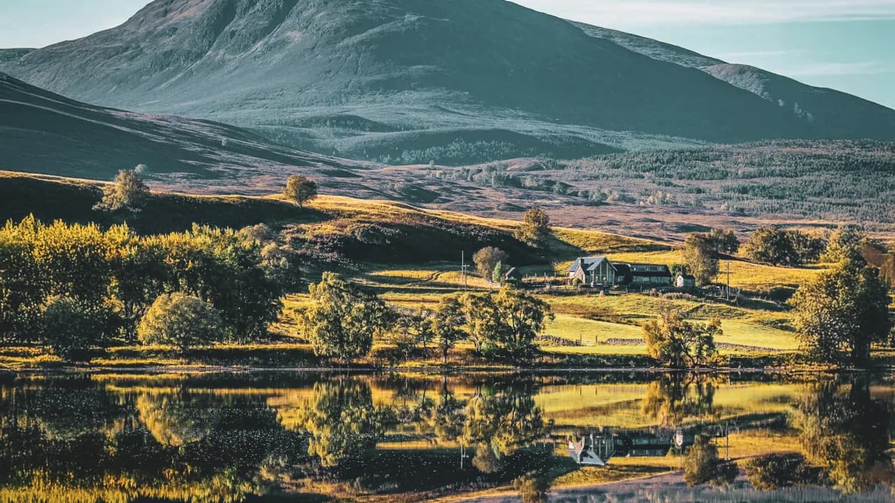 Schilderachtig landschap van de Schotse Hooglanden, majestueuze bergen, een rustig loch en weelderig groen.