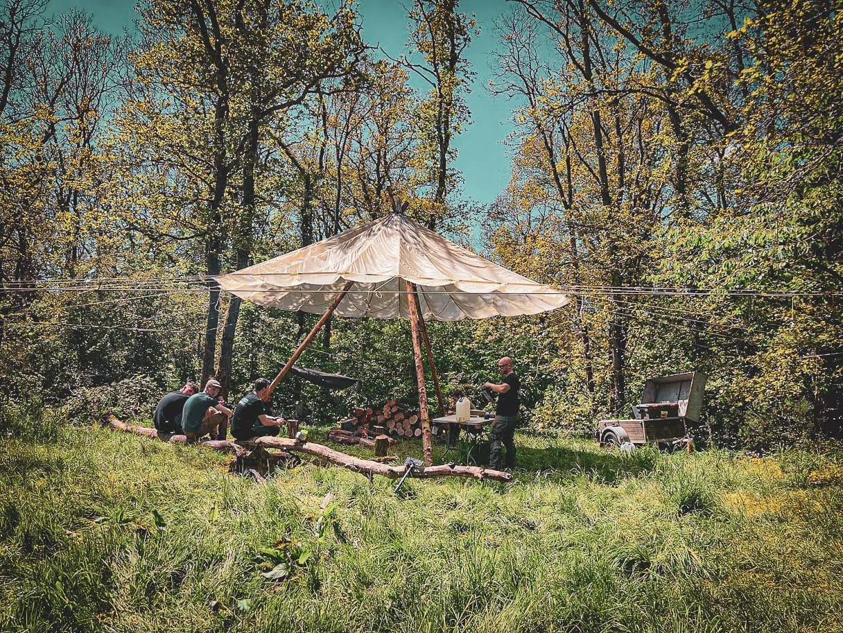 Een groep in de wildernis, onder tentdoek, leert te overleven in een groen bos.