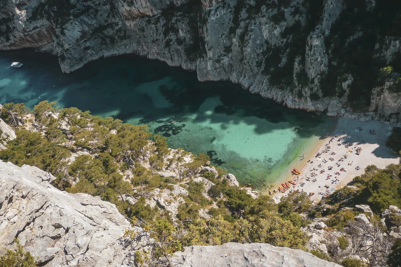 Vue panoramique des Calanques de Marseille, eaux turquoise, criques sauvages et plage ensoleillée.