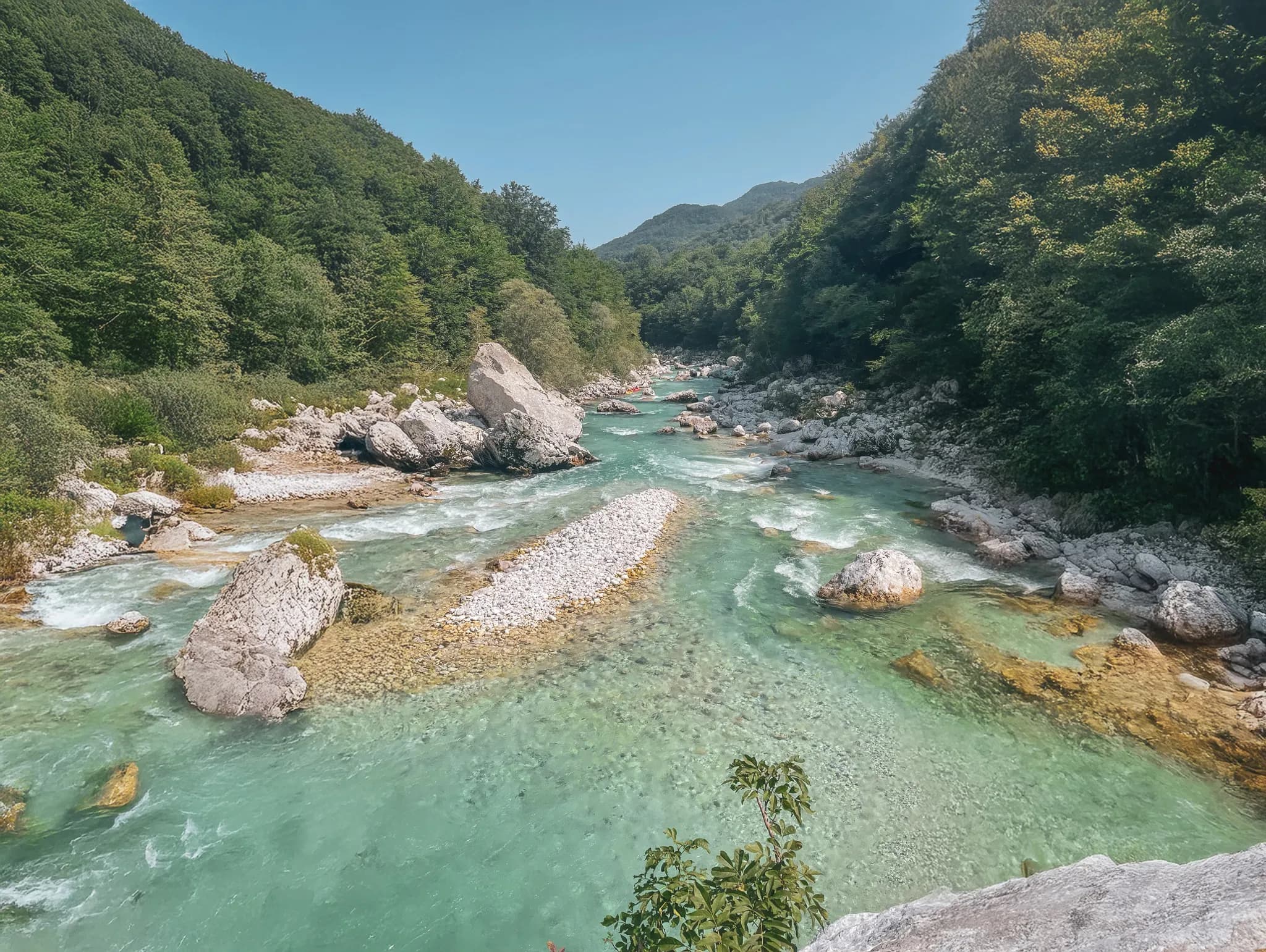 Rivière turquoise serpentant au cœur des montagnes verdoyantes de Slovénie, invitation à l'aventure.