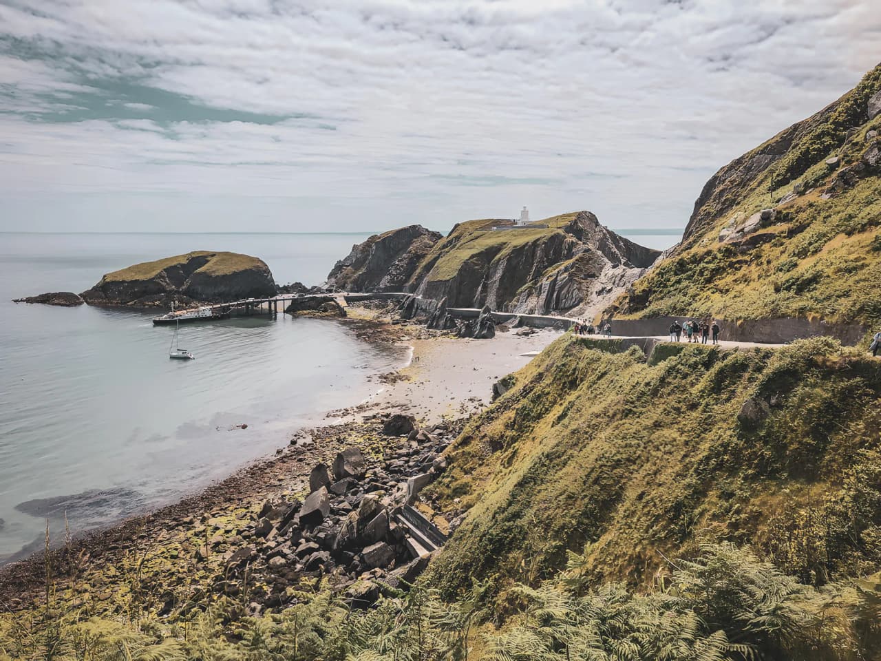 Vue pittoresque d'une côte galloise, montagnes verdoyantes et plage tranquille invitant à l'exploration.