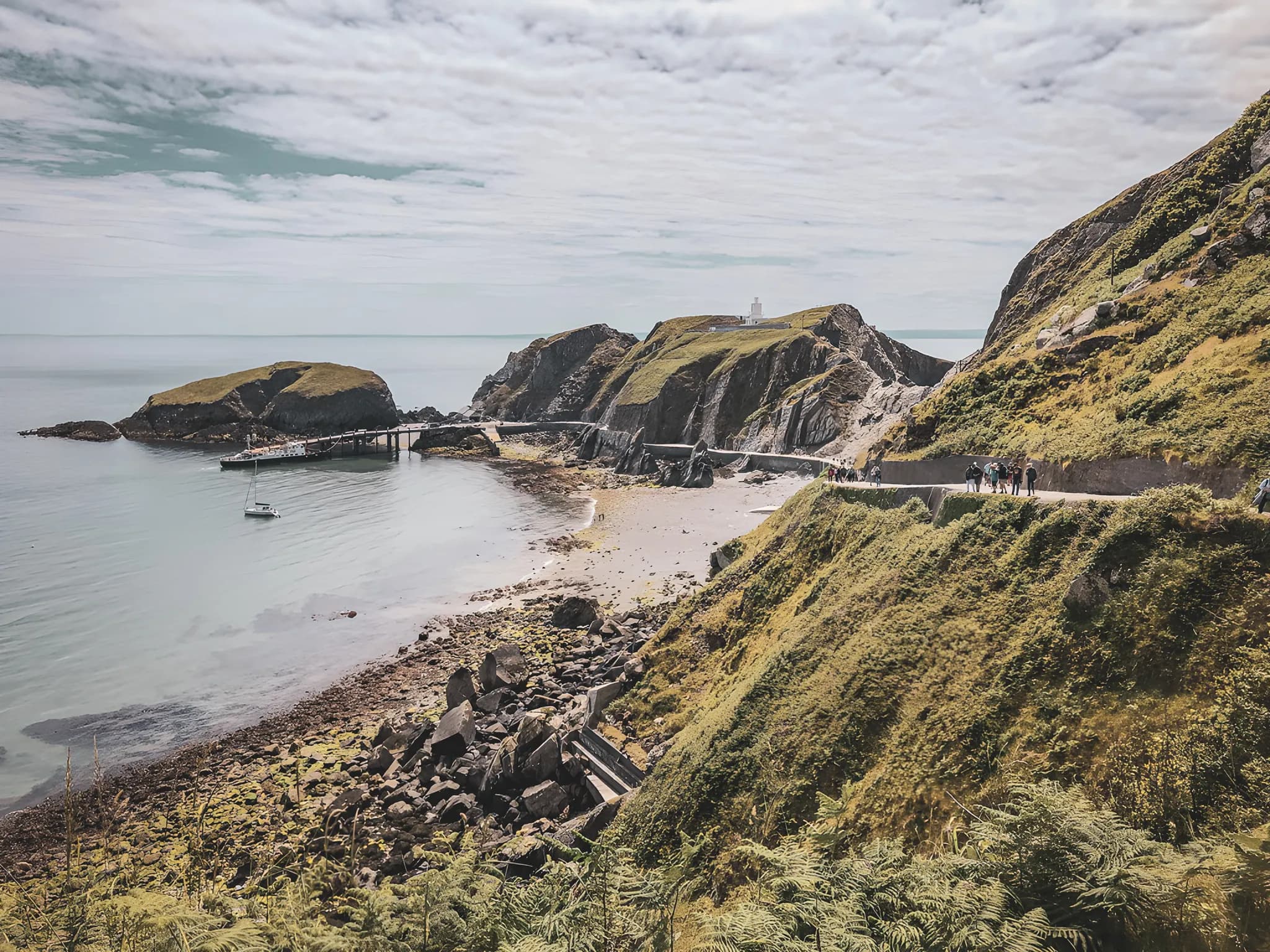 Vue pittoresque d'une côte galloise, montagnes verdoyantes et plage tranquille invitant à l'exploration.
