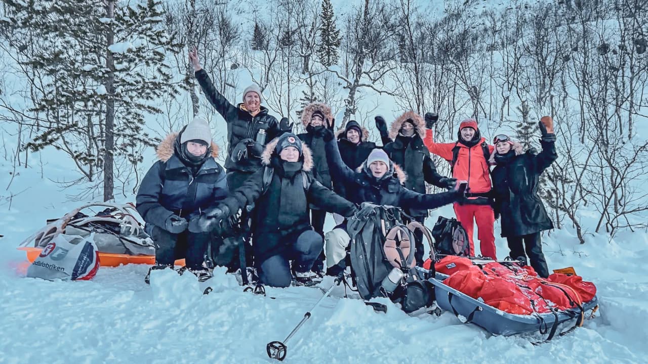 Een vrolijke groep op sneeuwschoenen, omringd door sneeuw, klaar voor een avontuur in Noors Lapland.