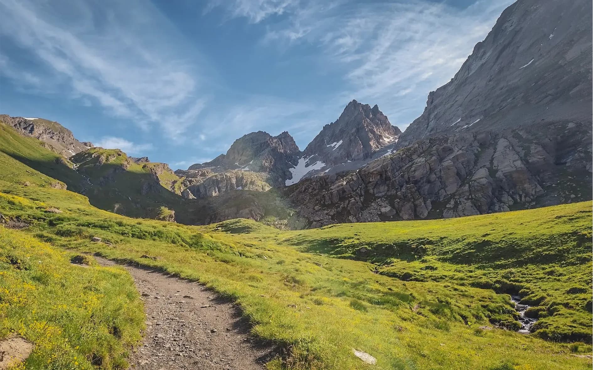 Green mountain scenery, winding paths leading to majestic peaks under blue skies.