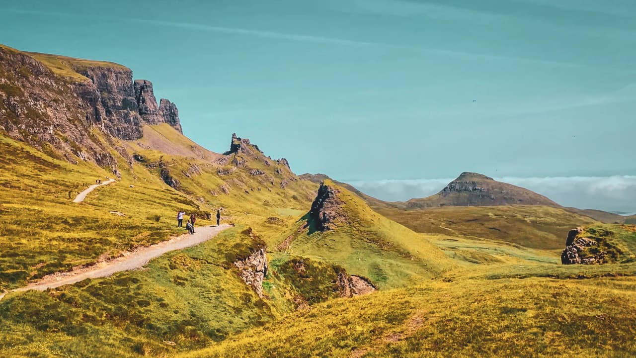 Wandelaars die de betoverende landschappen van het eiland Skye verkennen, tussen kliffen en groene heuvels.