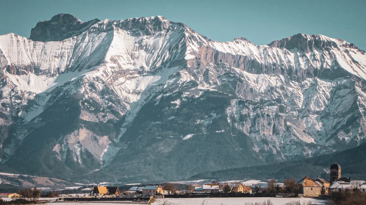 Majestueuze besneeuwde bergen onder een heldere hemel, een idyllisch landschap voor avonturiers.
