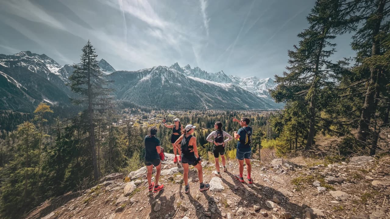 Vijf renners bewonderen het spectaculaire berglandschap van Chamonix, met de Mont Blanc op de achtergrond.
