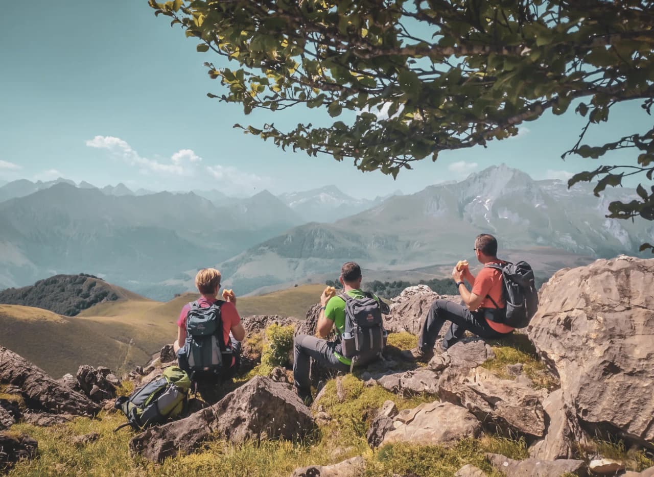 Trois randonneurs admirent un panorama montagnard dans les Pyrénées, évasion au cœur de la nature.