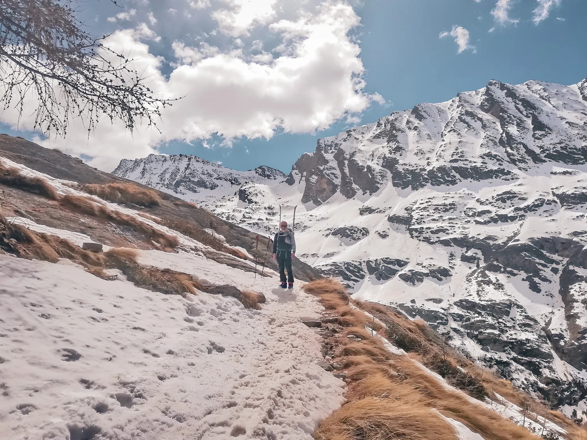 Randonneur sur un sentier enneigé avec des sommets majestueux en arrière-plan. Évasion alpine garantie!