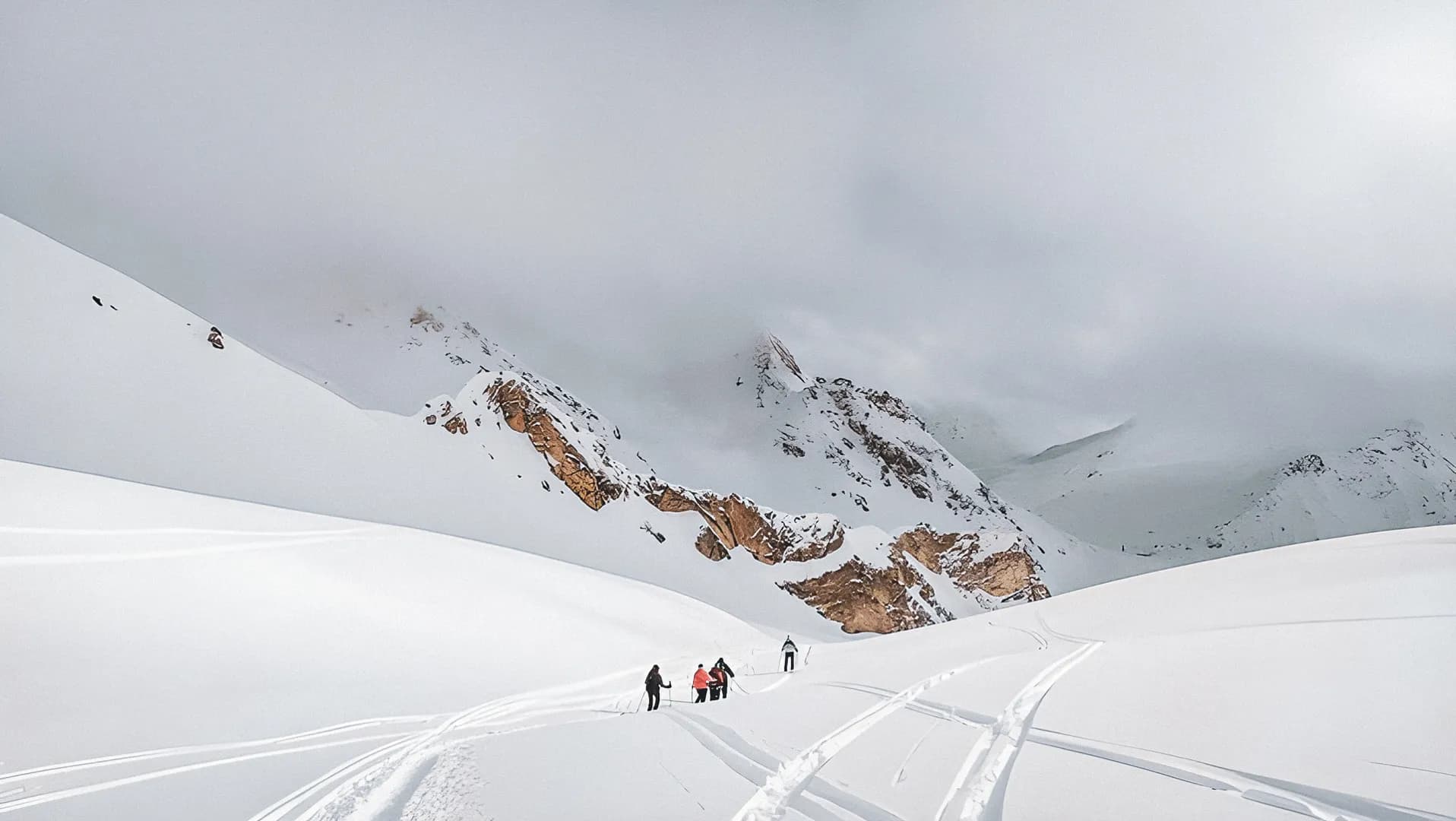 Wandelaars die op sneeuwschoenen een pad afdalen in de Alpen.