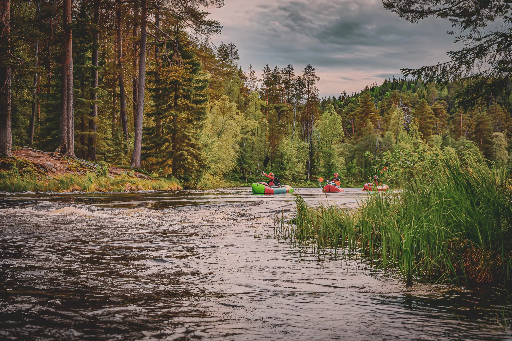 Adventurers in packraft navigate wild rivers surrounded by verdant forests.