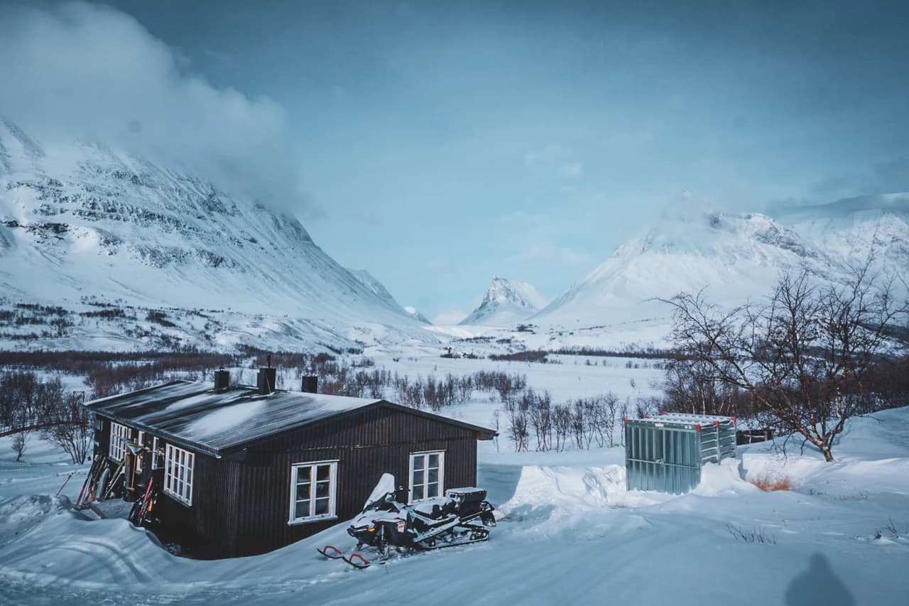 Een gastvrij Berghut onder besneeuwde bergen, een uitnodiging tot avontuur in Lapland.