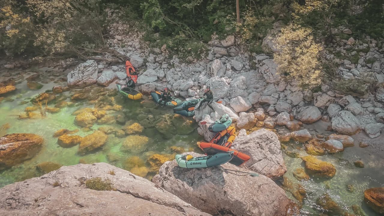 Colourful packrafts on rocks beside a crystal-clear river in Slovenia. A natural adventure!