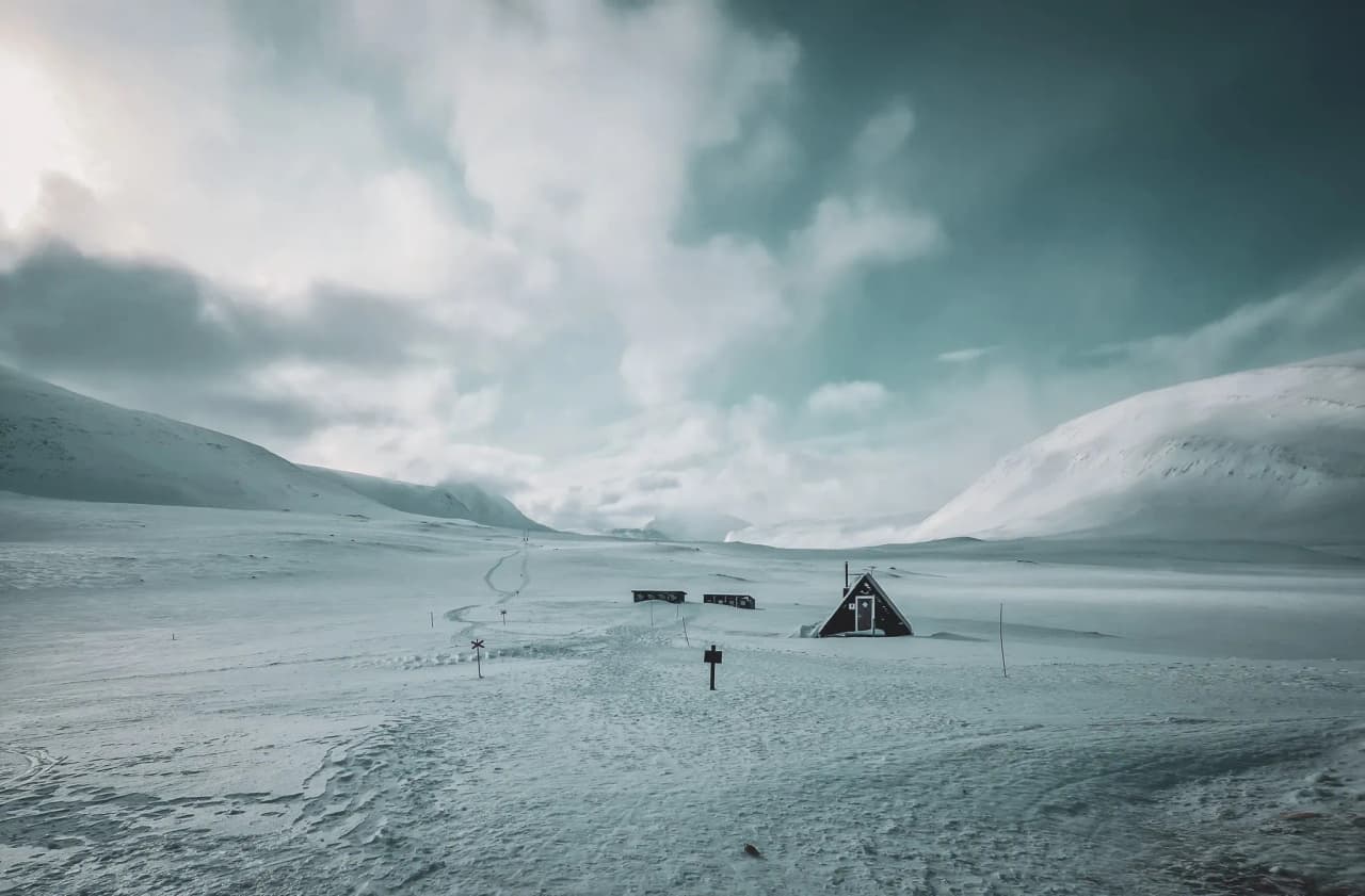 Een uitgestrekt besneeuwd landschap met majestueuze bergen en een gastvrij Berghut.