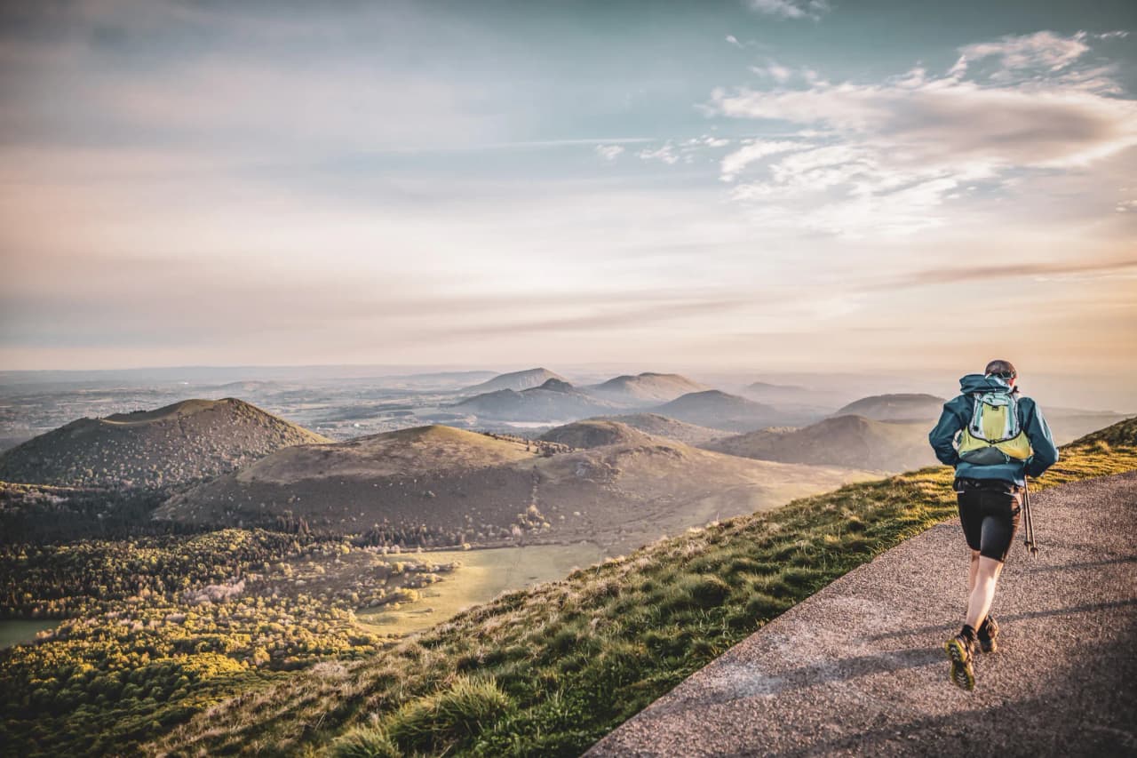 A hiker sets off along a path, with the breathtaking volcanic landscapes of the Auvergne.