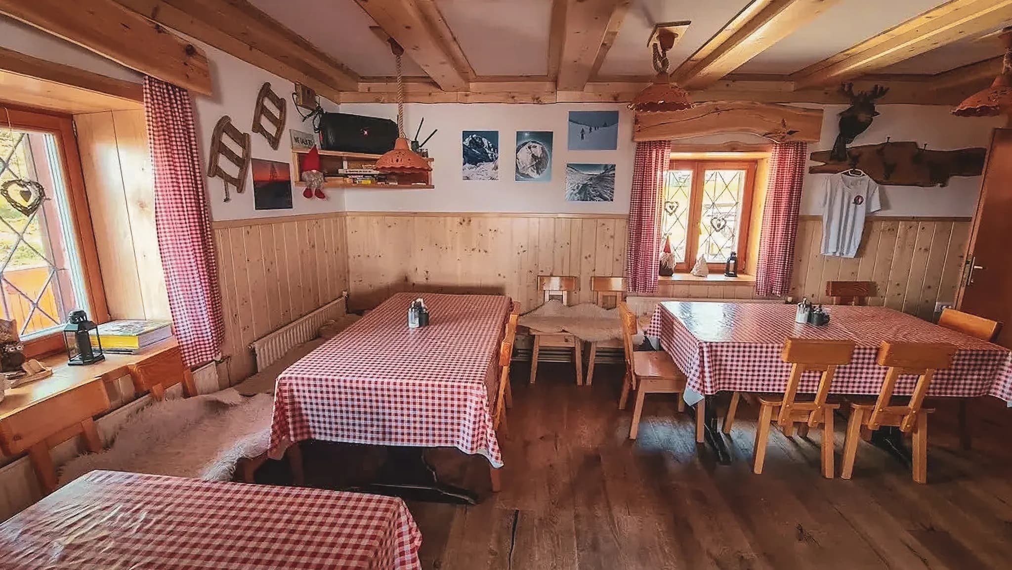 Intérieur chaleureux d'un chalet alpin, tables à carreaux, bois chaleureux et vues inspirantes.