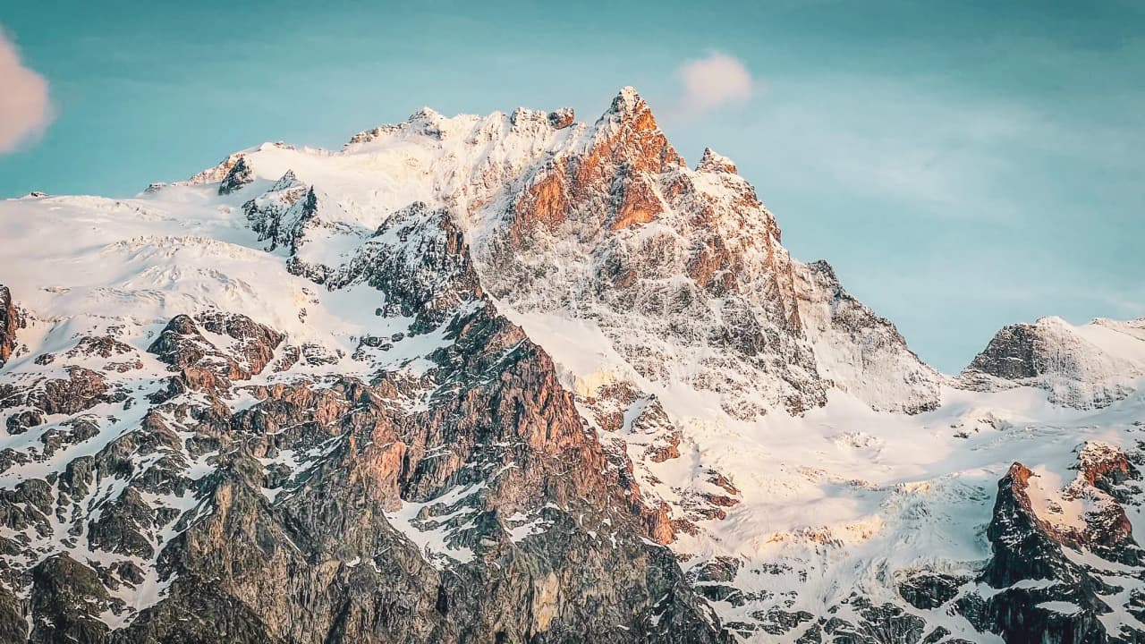 Montagnes majestueuses enneigées au coucher du soleil, invitant à l'aventure alpine.