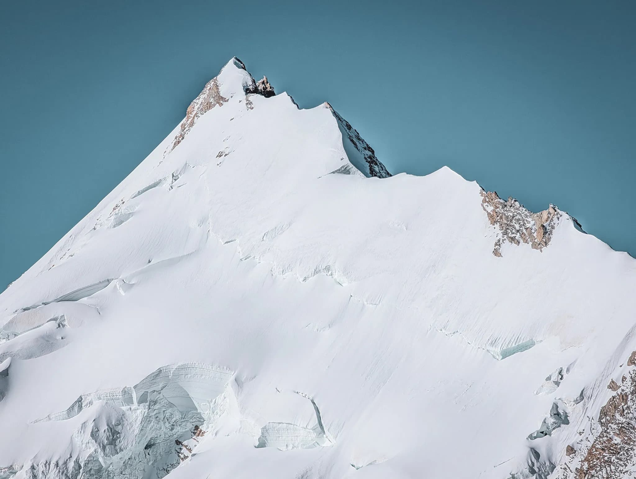 A majestic mountain covered in snow under a blue sky, an invitation to alpine adventure.