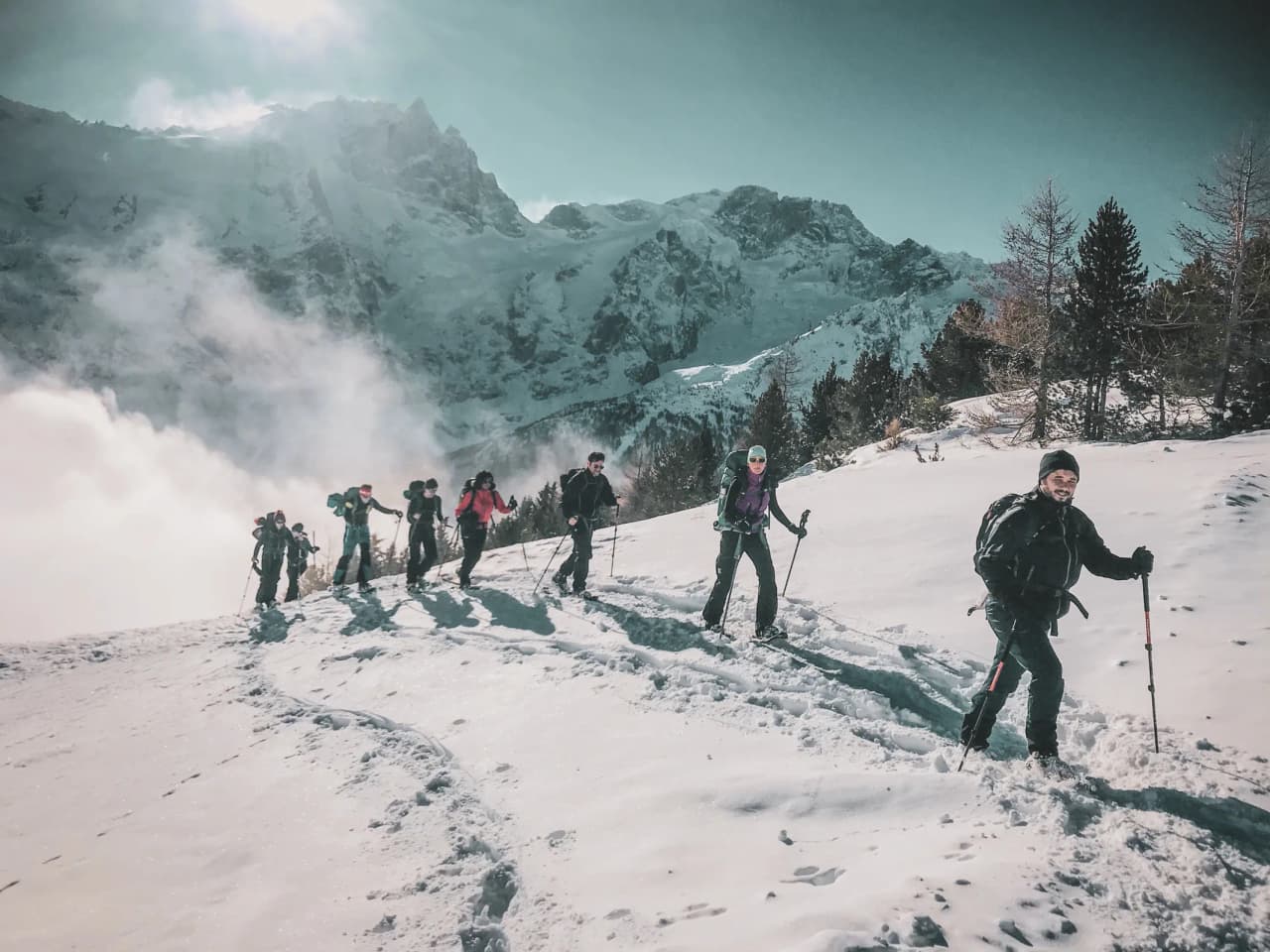 Groupe de randonneurs en raquettes sur un sentier neigeux, face aux majestueux glaciers des Écrins.