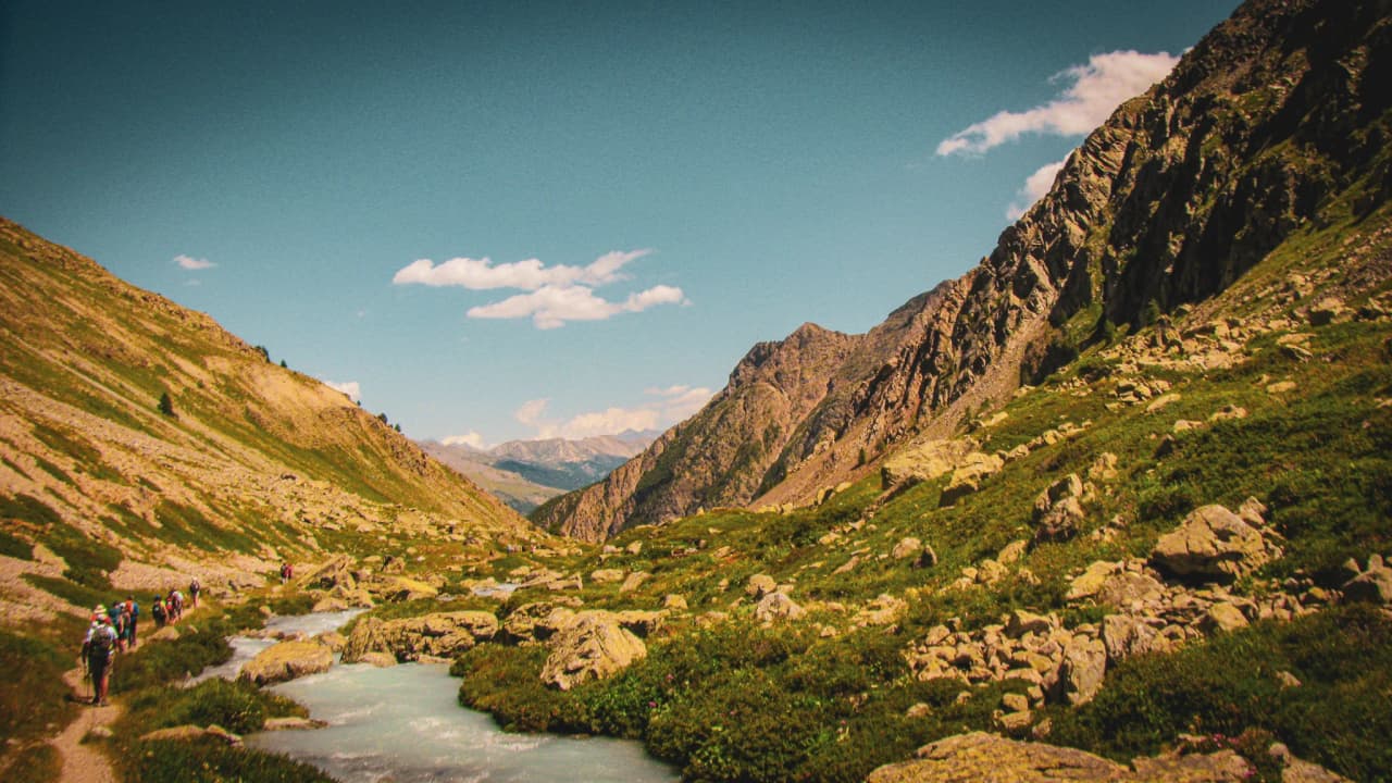 A peaceful hike in the Écrins, with a stream and majestic mountains in the background.