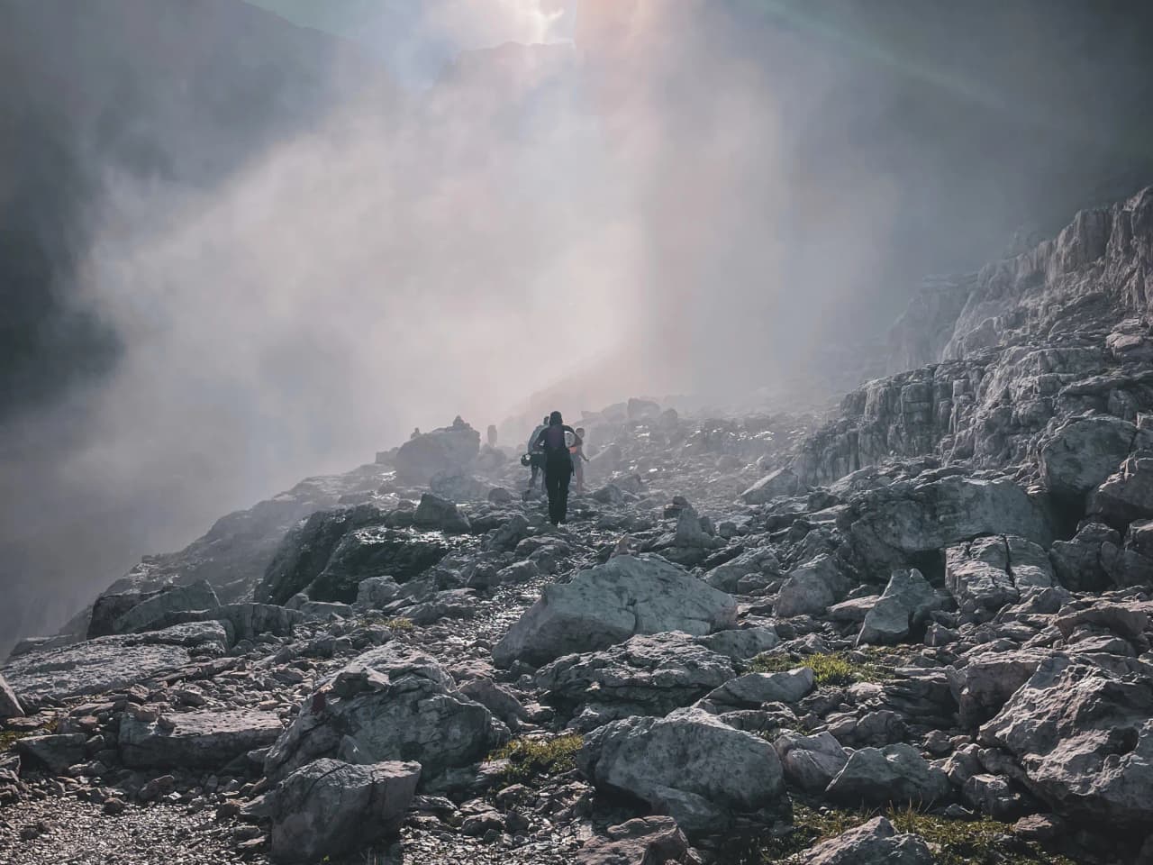 A solitary hiker on a rocky path, shrouded in mist in the majestic Dolomites.