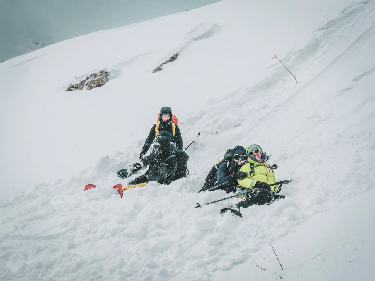 Trois randonneurs en raquettes s'amusent dans la neige face aux majestueux glaciers des Écrins.