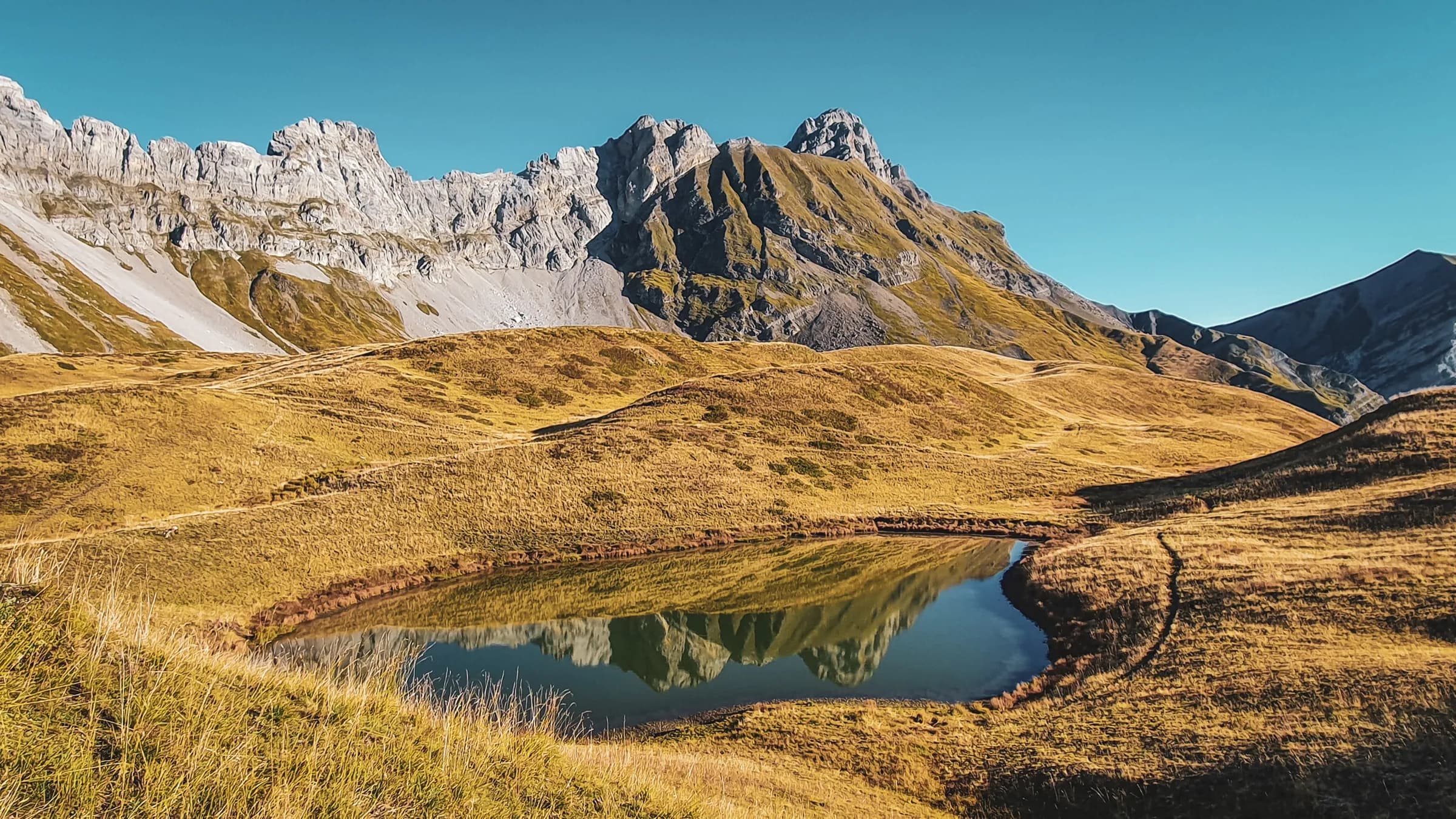 A peaceful lake surrounded by majestic mountains, an invitation to alpine adventure.