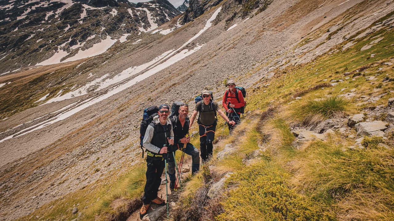 Five smiling hikers, equipped for adventure, on a spectacular Alpine trail.