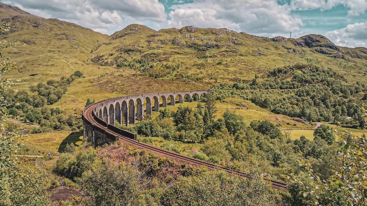 Een reiziger bewondert het viaduct in de groene Schotse Hooglanden. Natuur en avontuur.
