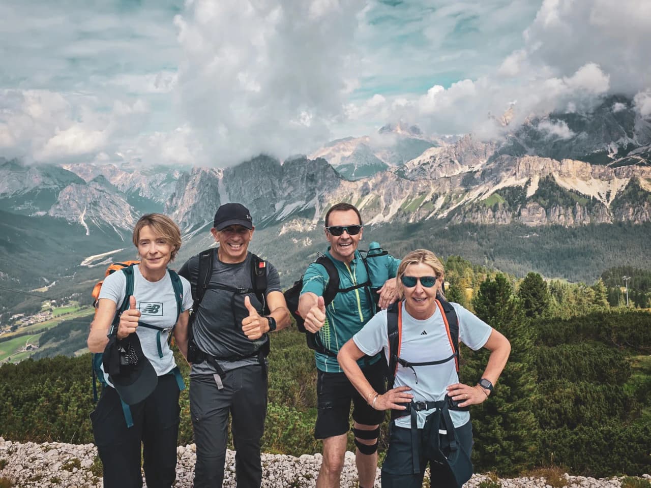 Four smiling hikers pose with spectacular Dolomite scenery in the background.