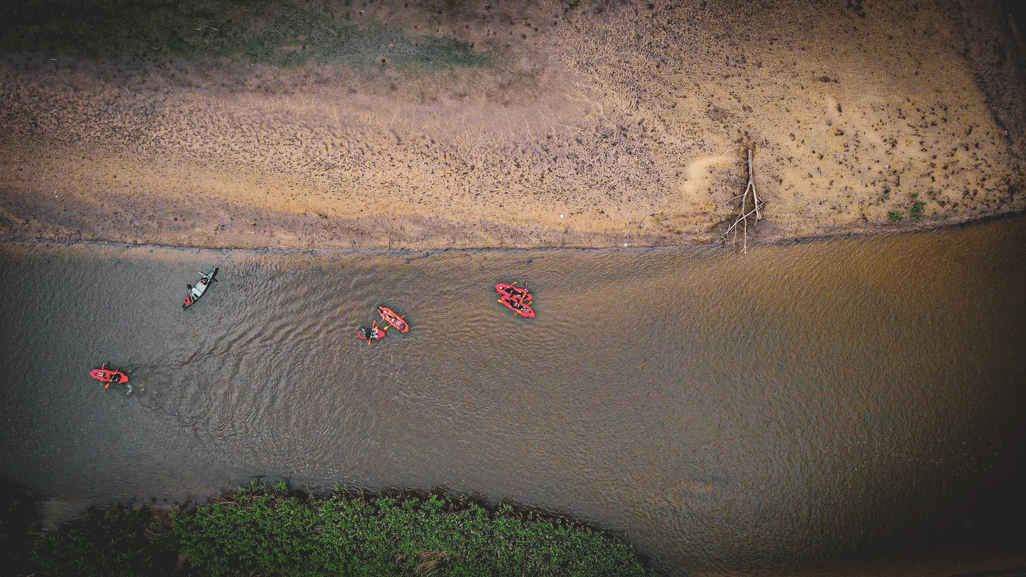 Ensemble de packrafts rouges glissant paisiblement sur une rivière entourée de nature, invitant à l'aventure.