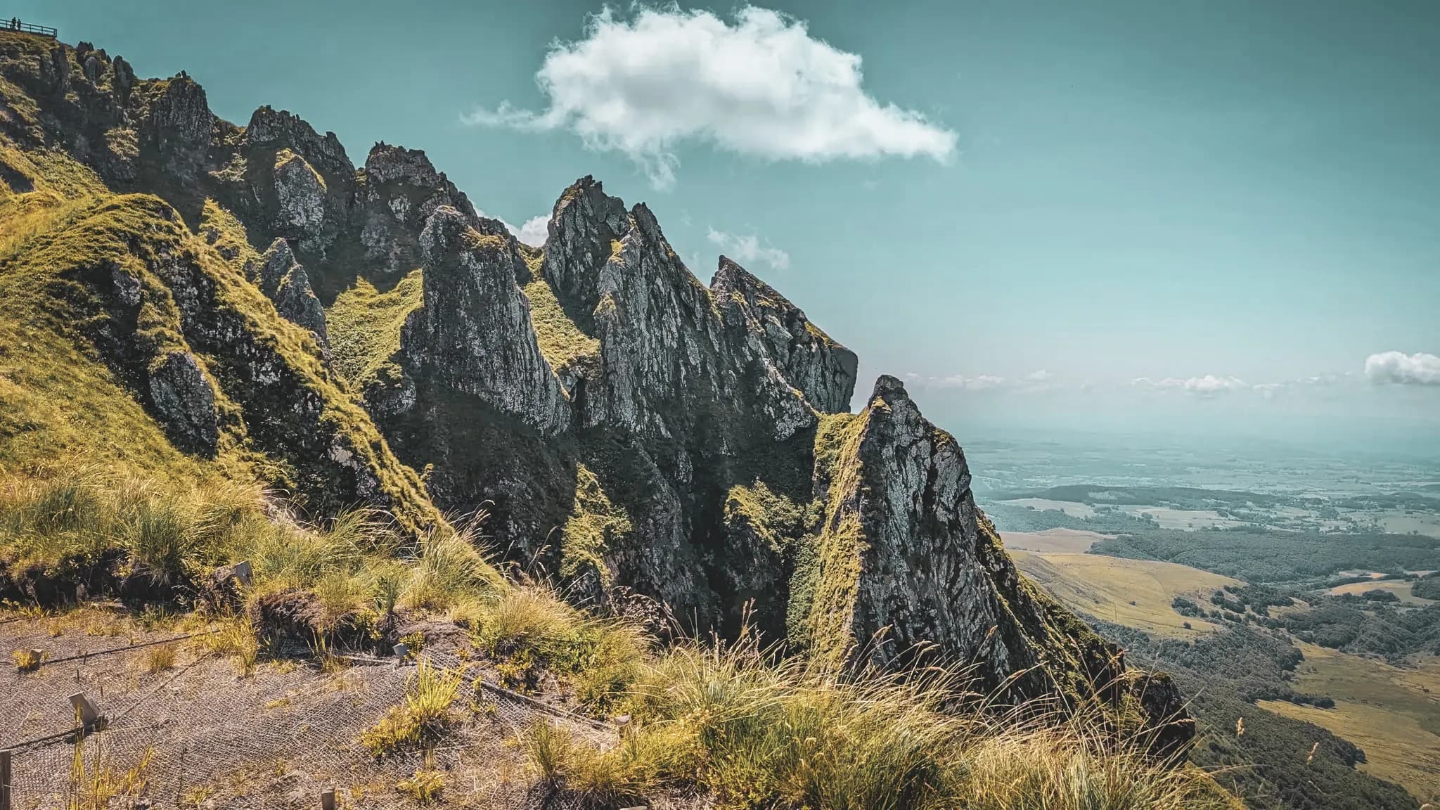 Een adembenemend panorama van de vulkanen van de Auvergne, met steile bergkammen onder een blauwe hemel.
