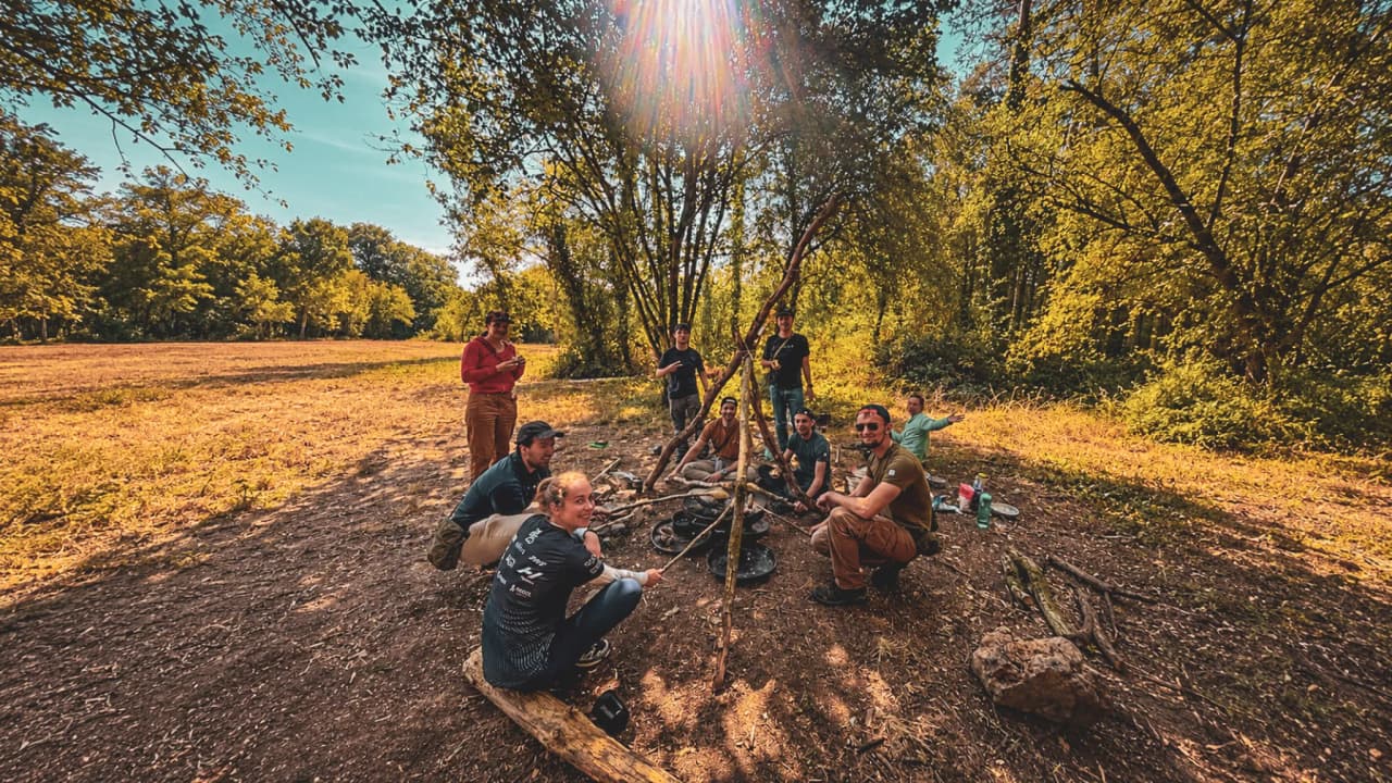 Groupe d'aventuriers en pleine nature, construisant un abri en forêt, ambiance conviviale et chaleureuse.