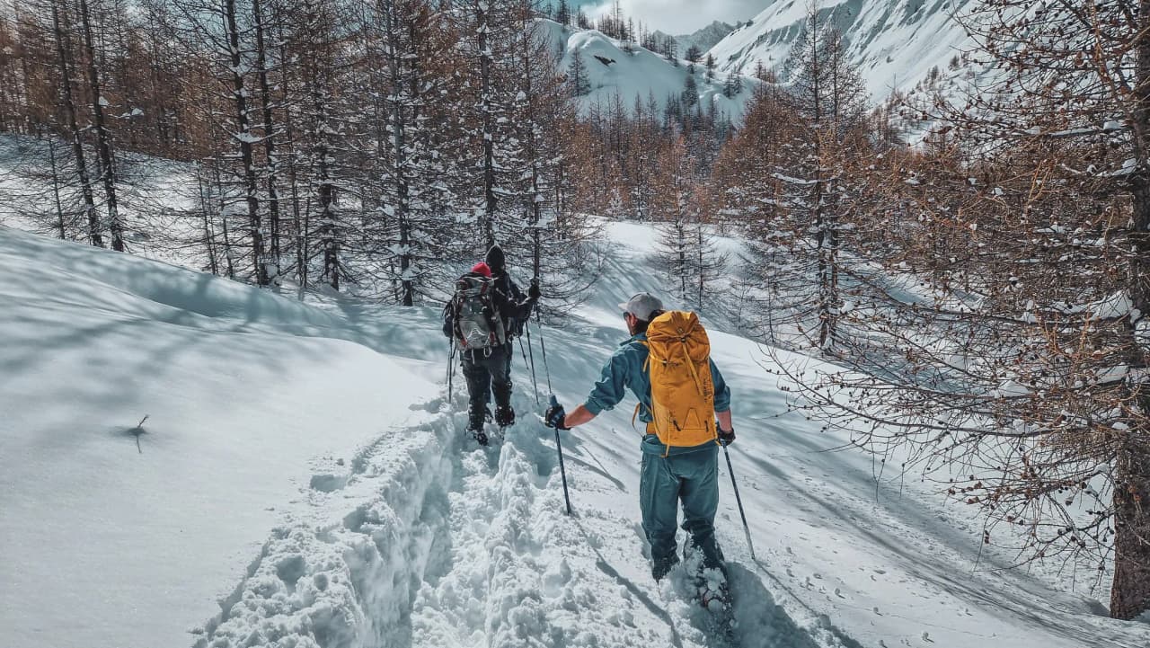 Deux randonneurs à raquettes parcourent une neige vierge en Haute-Ubaye, sous un ciel ensoleillé.