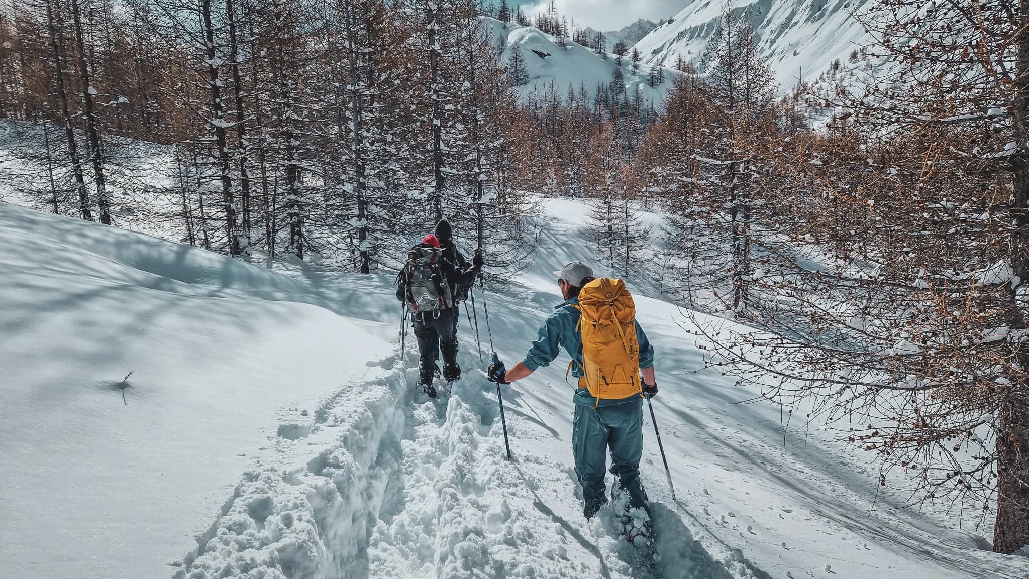 Twee wandelaars op sneeuwschoenen die maagdelijke sneeuw bedekken in Haute-Ubaye, onder een zonnige hemel.