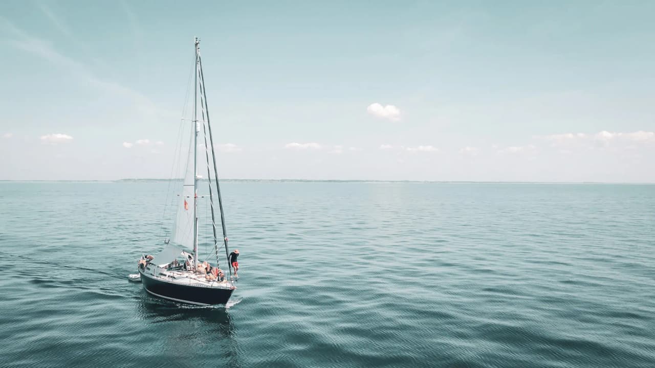 A sailboat sailing peacefully on turquoise waters under a sunny sky.