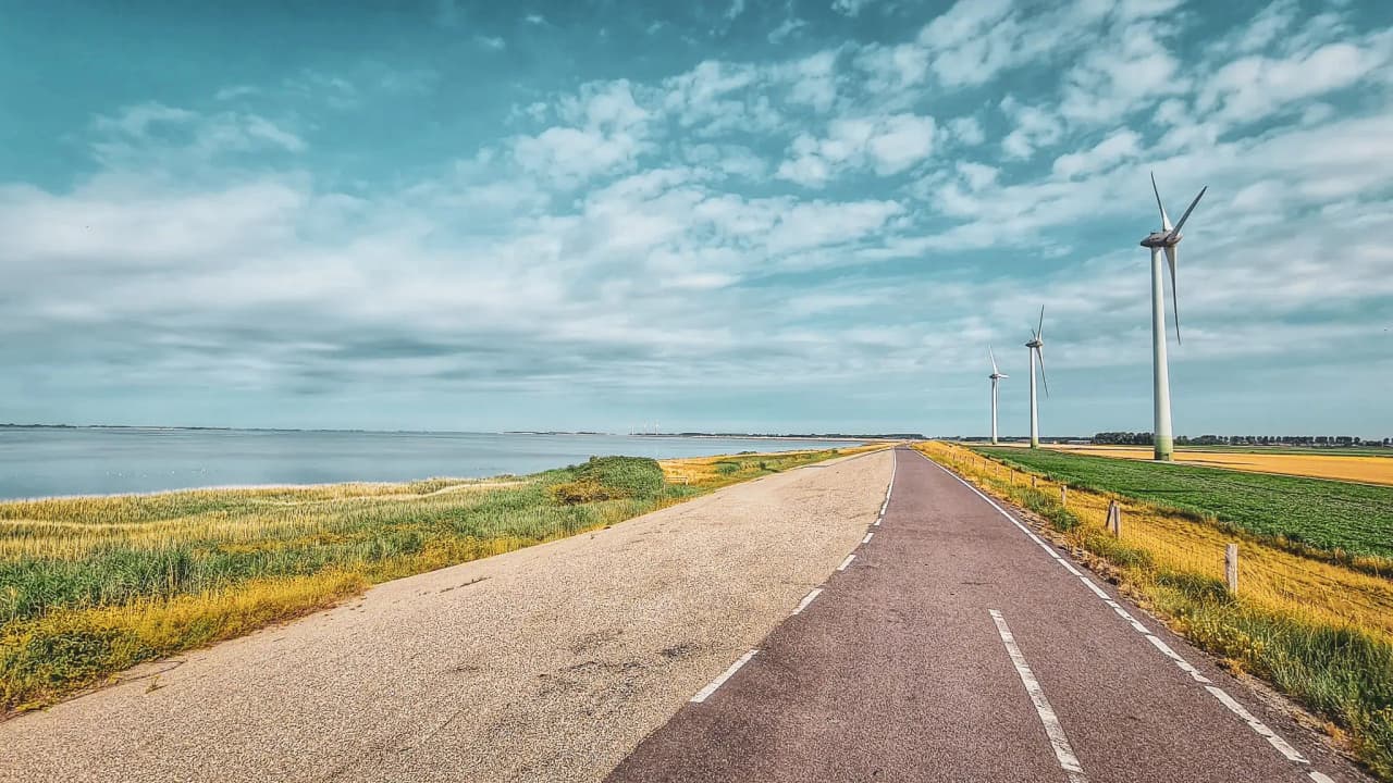 Road with wind turbines by the sea in the Netherlands