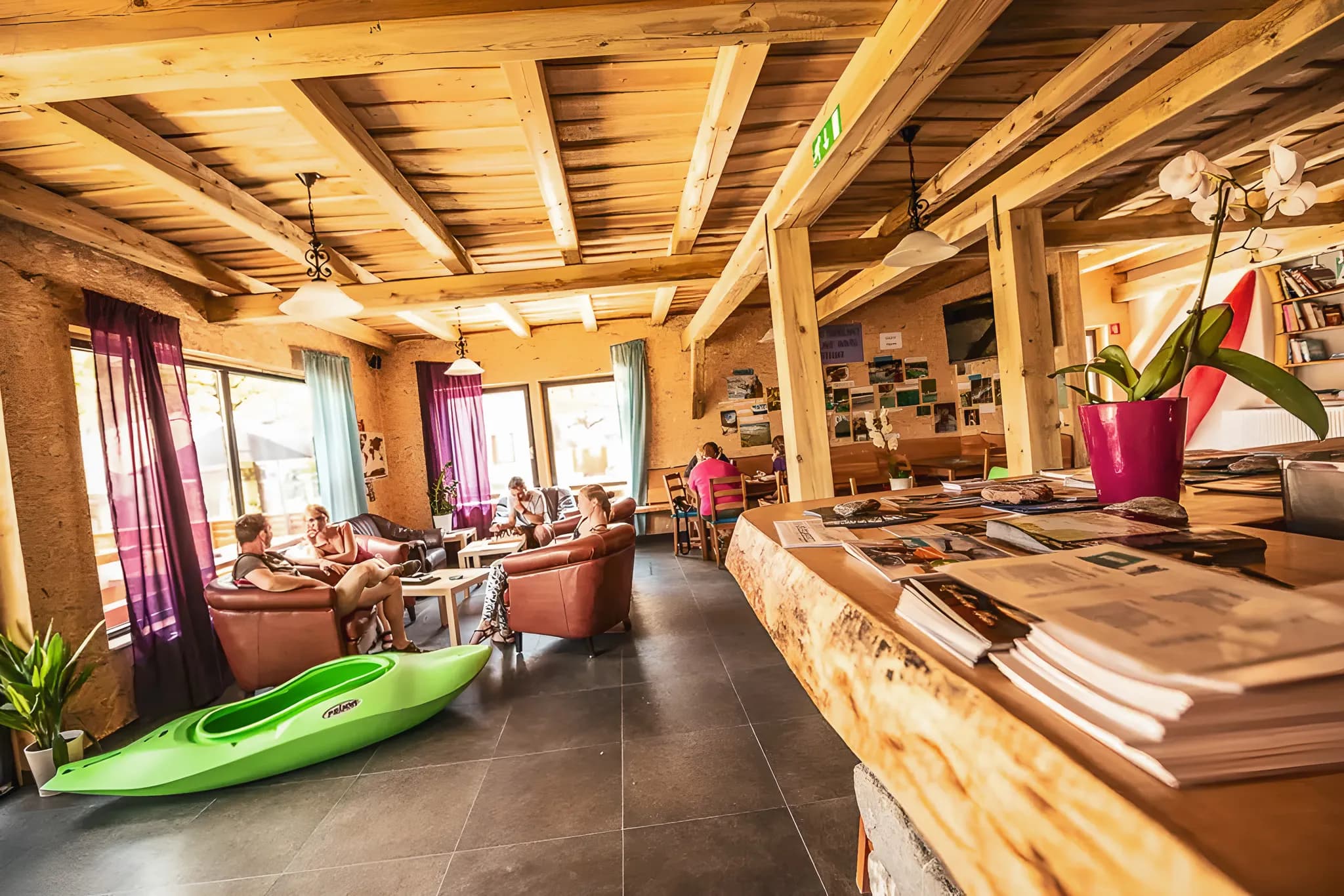 Un salon convivial avec des canapés, un kayak vert et des voyageurs prêts à explorer la Slovénie.