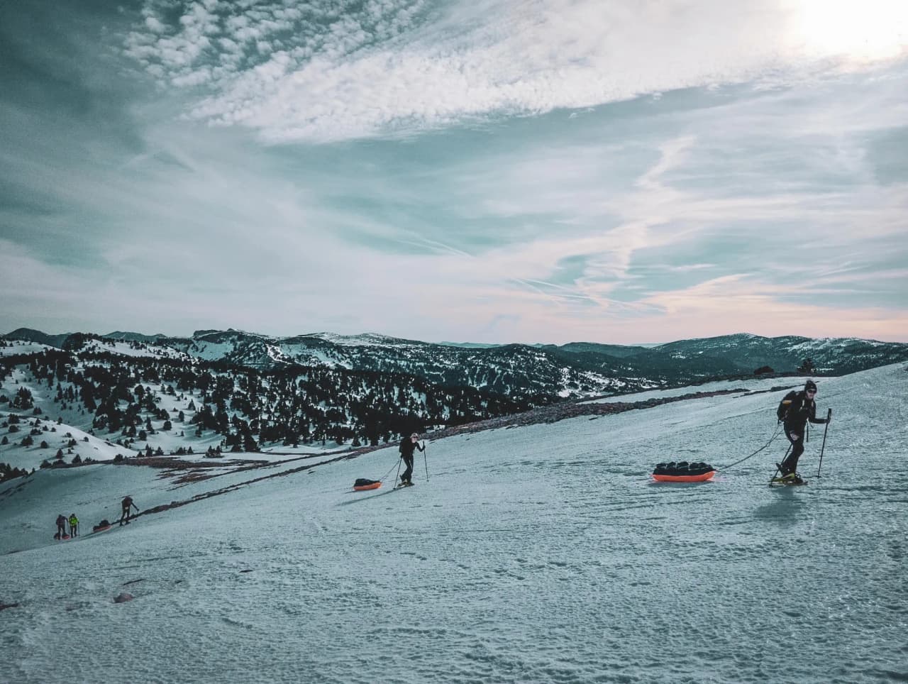A snowshoeing expedition across a vast snow-covered plateau, with mountains in the background.