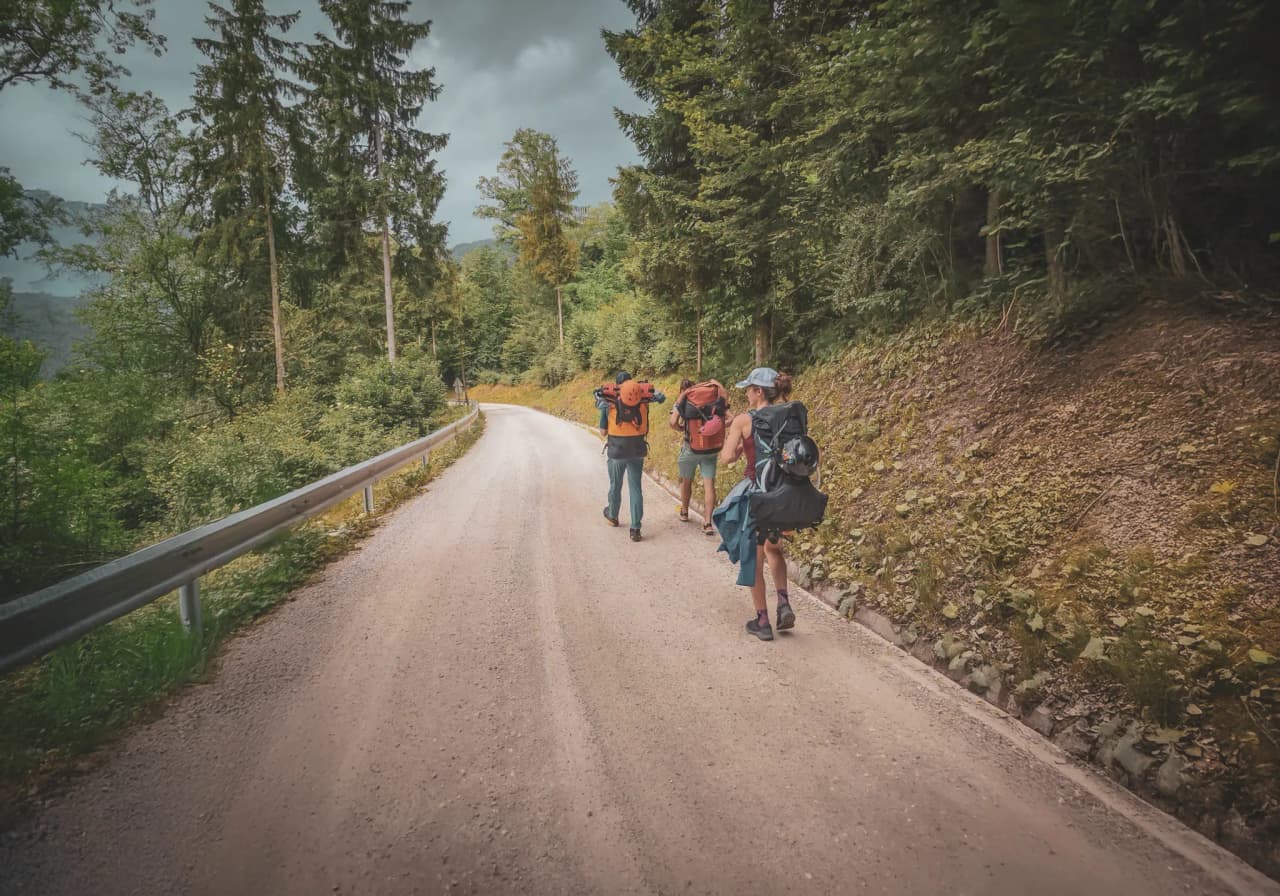 A group of hikers on a gravel path surrounded by greenery, ready for an adventure in Slovenia.