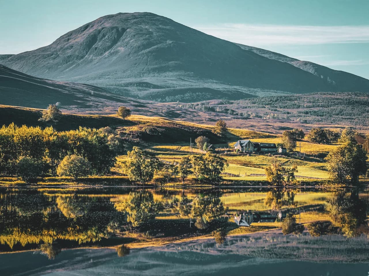 Schilderachtig landschap van de Schotse Hooglanden, majestueuze bergen, een rustig loch en weelderig groen.
