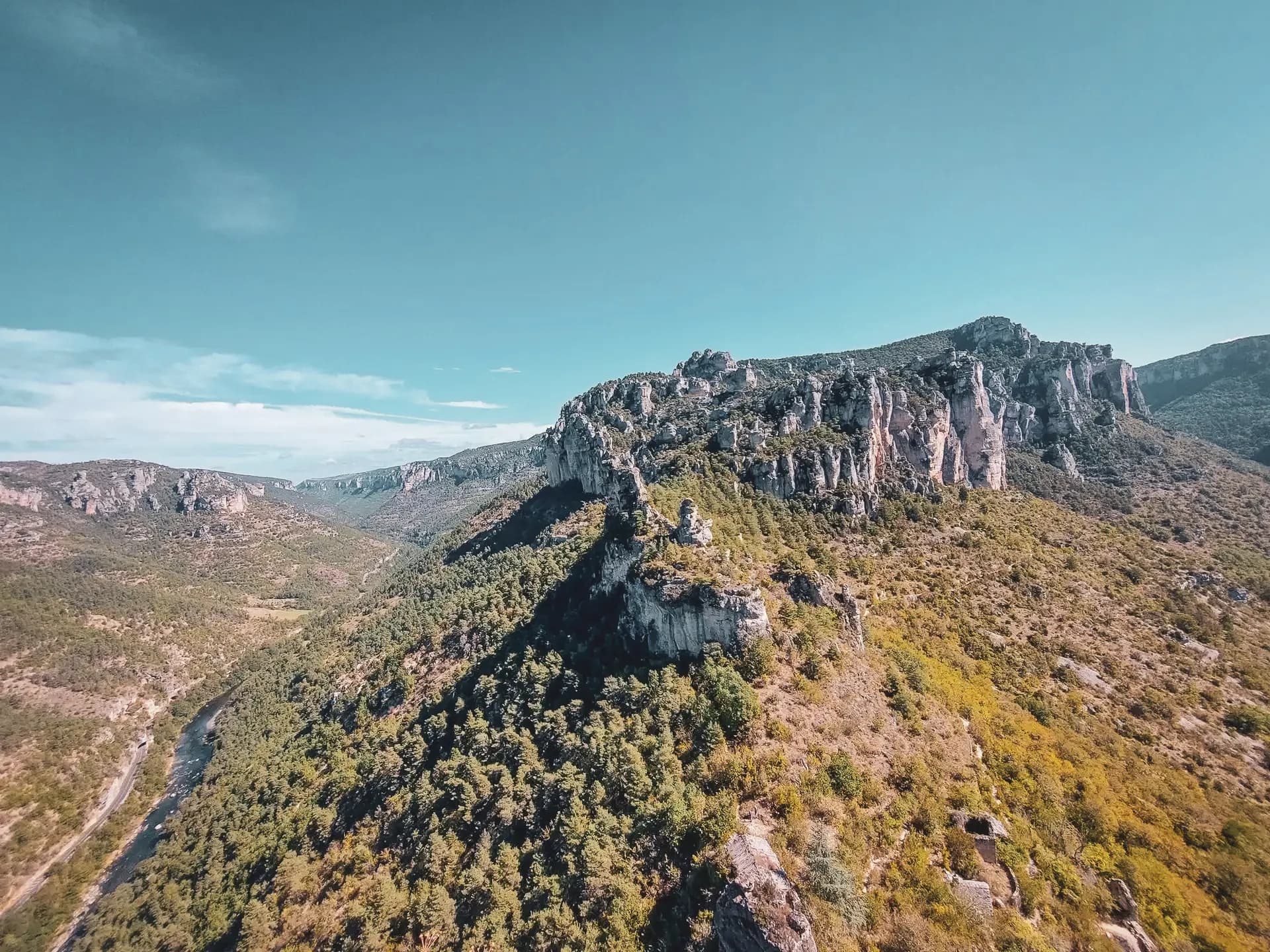 Panorama ensoleillé des Gorges du Tarn, avec falaises majestueuses et nature verdoyante.