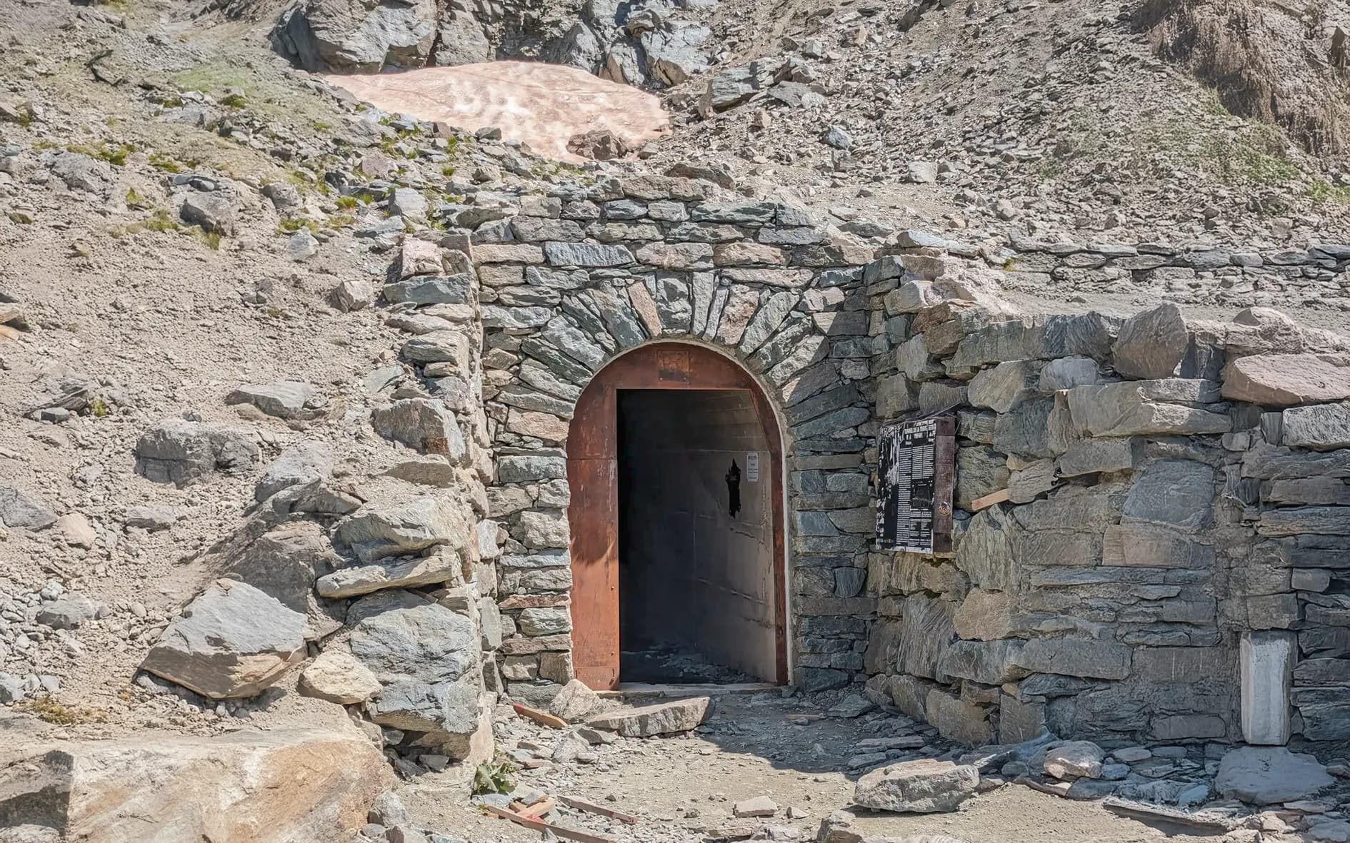 The stone entrance to a mountain shelter, surrounded by rocky landscapes, is an invitation to adventure.