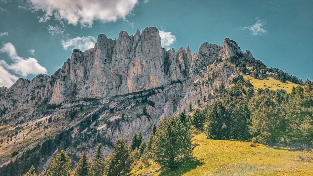 Majestic Mont Aiguille, towering cliffs against a backdrop of sky and welcoming greenery.