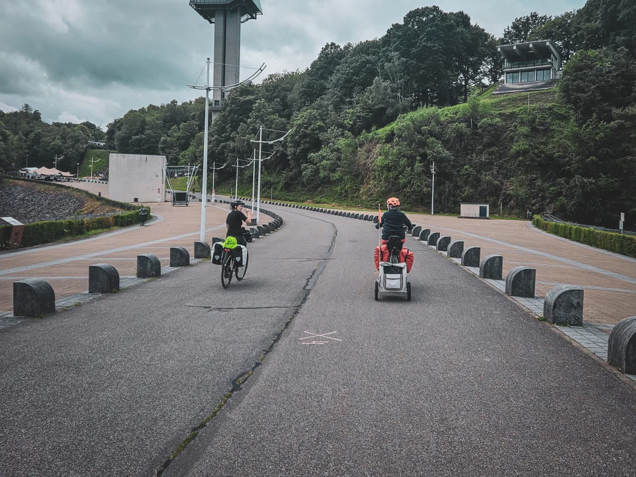 Deux cyclistes empruntent une route paisible, entourés de verdure, vers l'aventure en nature.