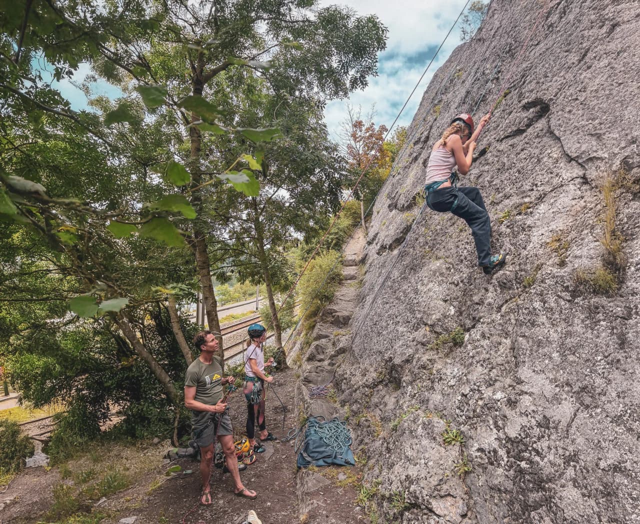 A climber takes up climbing on a green cliff surrounded by nature.