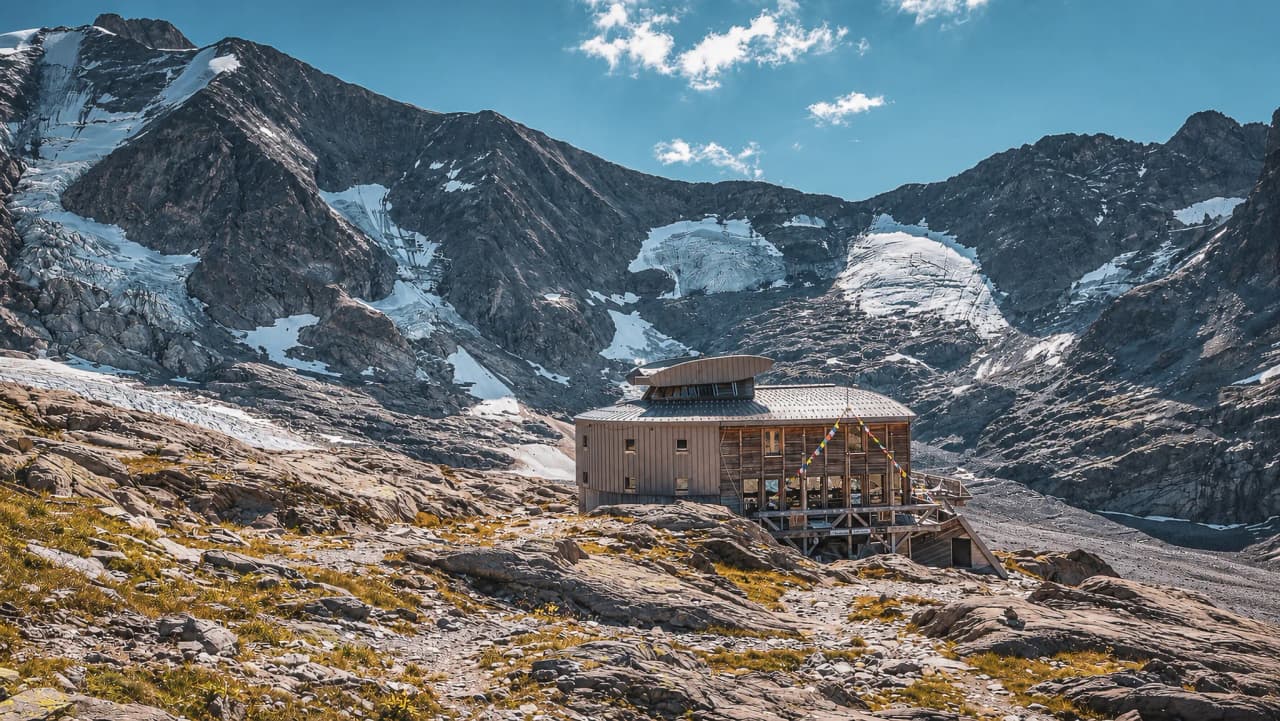 Een houten Berghut met uitzicht op de majestueuze Dômes de Miage, ideaal voor een avontuur in de Alpen.