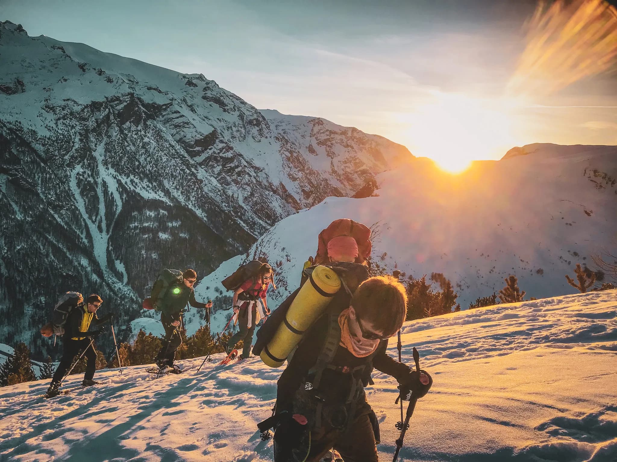 Een groep sneeuwschoenrenners tijdens een beklimming bij zonsondergang in de Meije in Frankrijk.